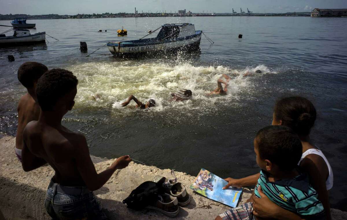 Kids watch a swimming competition in Havana Bay during a small fair in the Casablanca neighborhood of Havana, Cuba, Thursday, July 16, 2015. Casablanca residents have brought back lost traditions to their 420-year-old neighborhood, including this game in which swimmers start out from the anchored boats and swim to and from from a nearby dock. The winner is awarded 100 Cuban pesos, or about $4 dollars. (AP Photo/Ramon Espinosa)