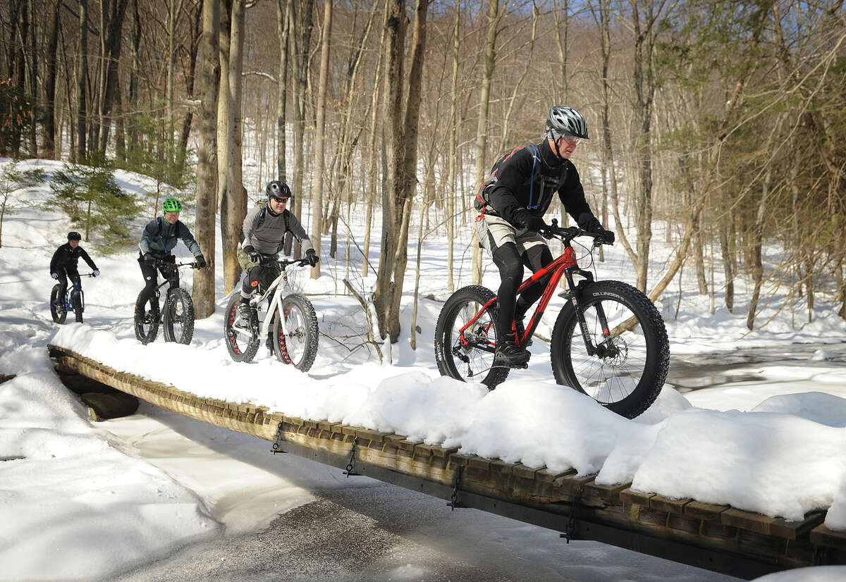 From left; Gena Deribeaux, Charlie Zylstra, Guy Walker, and Stephen Dineley, all of Trumbull, ride their fat bikes single file across the Pequonnock River at Indian Ledge Park in Trumbull, Conn. recently. The bikes, designed for riding on snow with wide forks and knobby balloon tires, are growing in popularity.