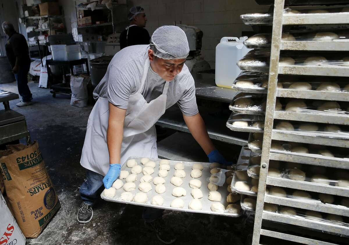 A bakery worker puts the finished individual dough pieces into a rack, they will be flattened and baked later at Hamati. Aroma's Hamati Bakery in San Bruno, Calif. makes homemade breads including pita, zaatar bread and sesame rings.