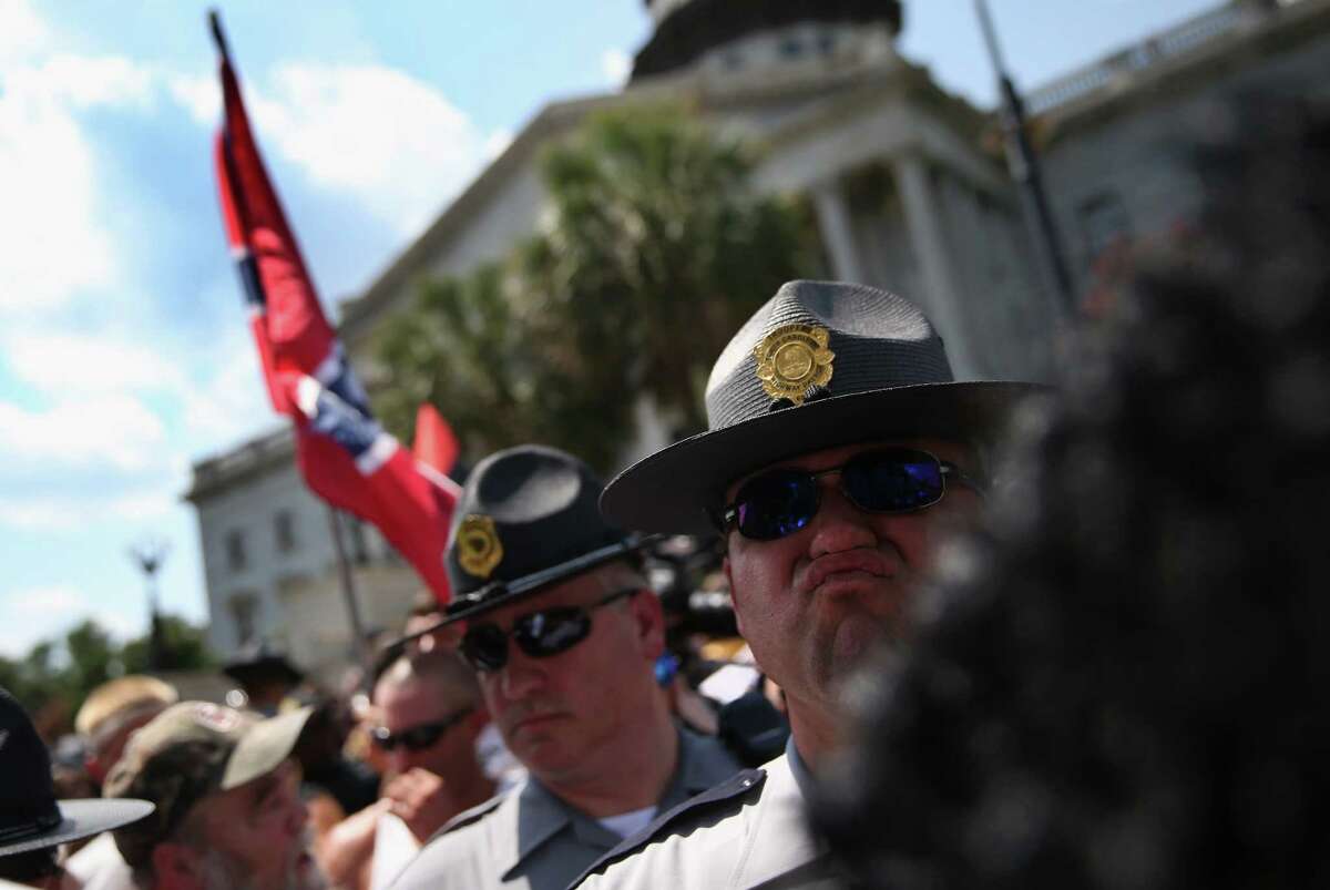 Police stand guard as Ku Klux Klan members arrive for a demonstration at the state house building on July 18, 2015 in Columbia, South Carolina. The KKK protested the removal of the Confederate flag from the state house grounds and shouted racial slurs against minorities, as law enforcement tried to prevent violence between the opposing groups.
