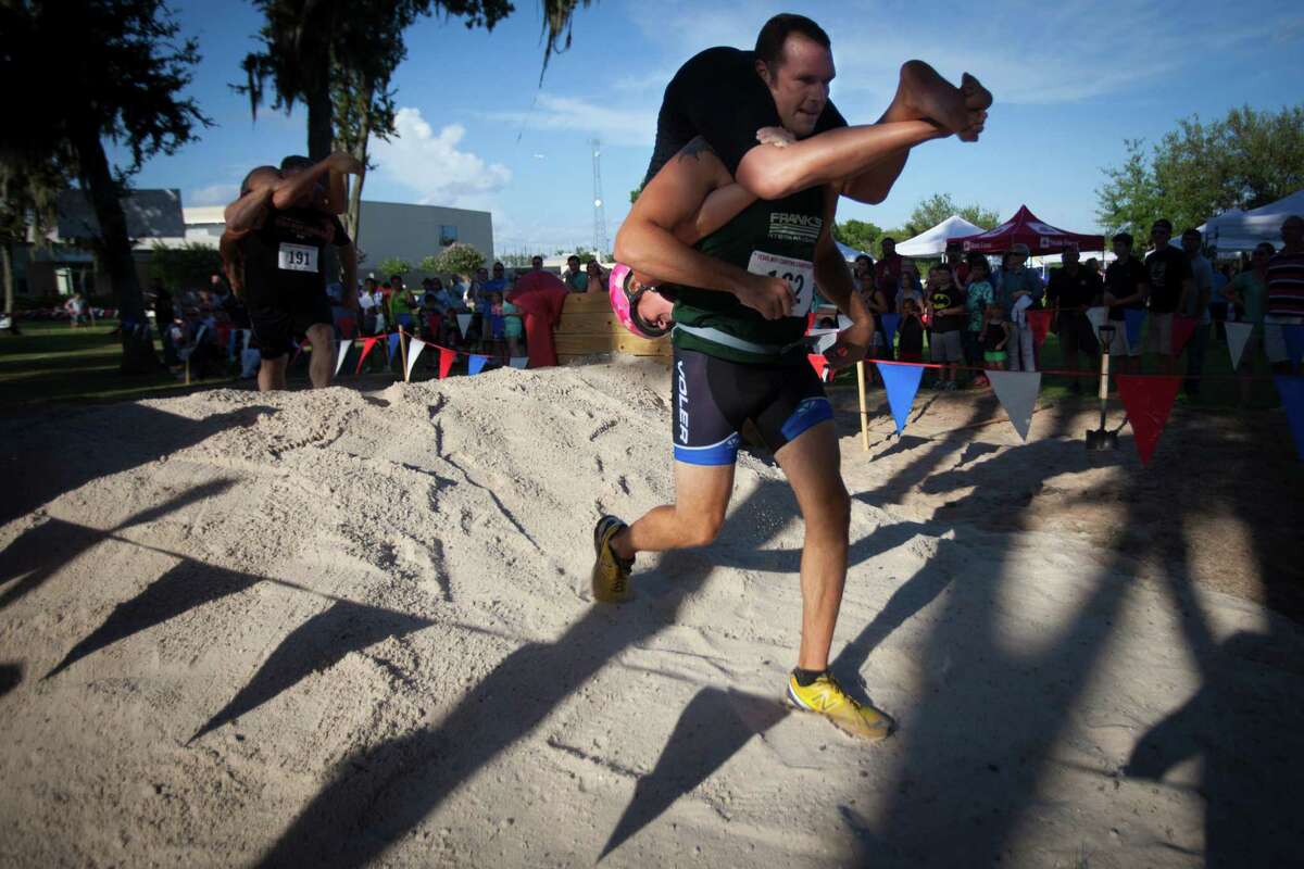 Drew Ludlow carries his wife Jennifer Ludlow during the 2015 Texas Wife Carrying Championship, Saturday, July 18, 2015, in Houston.