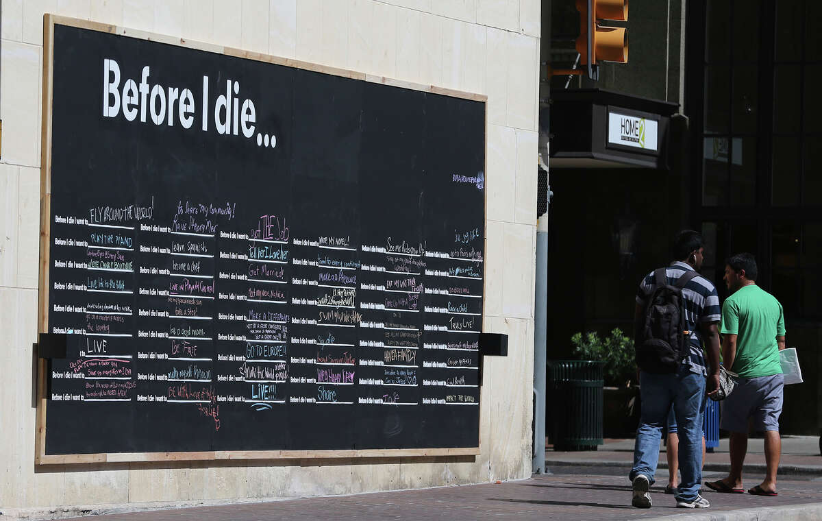 Pedestrians pass the "Before I die" wall at the corner of Navarro and Houston streets in July. The interactive public art exhibit was started by artist Candy Chang in 2011. It was part of an initiative that considers art as part of the formula for a more dynamic downtown.