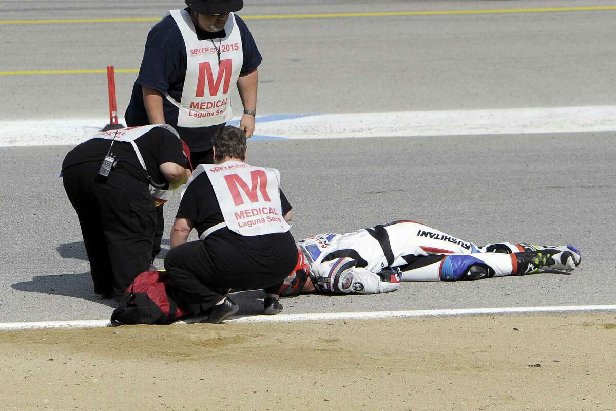 In this Sunday, July 19, 2015, photo, medical and track personnel attend to Spanish rider Bernat Martinez after a chain reaction crash on the first lap of a World Superbike race at Mazda Raceway at Laguna Seca in Monterey, Calif. Two Spanish racers were killed in the crash. Race organizers MotoAmerica identified the dead as 35-year-old Bernat Martinez and 27-year-old Daniel Rivas Fernandez. Both were taken to hospitals, where they later died. (Nic Coury/Monterey County Weekly via AP) MANDATORY CREDIT FOR PAPER AND PHOTOGRAPHER. MONTEREY HERALD OUT , SALINAS CALIFORNIAN OUT , SANTA CRUZ SENTINEL OUT , SAN JOSE MERCURY OUT , LOCAL TV OUT