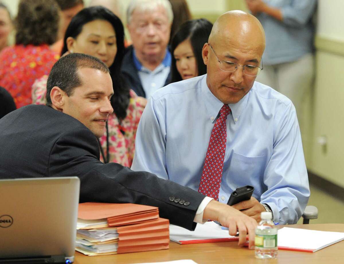 Attorney Daniel Young, left, and Greenwich High School band director John Yoon look over papers during Yoon's hearing at the Board of Education building in Greenwich, Conn. Tuesday, July 14, 2015. Yoon has been suspended for the past two months after he was allegedly found to have bullied two students this year.