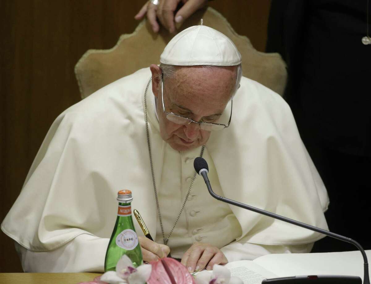 Pope Francis signs a declaration in the Synod Hall during a conference on Modern Slavery and Climate Change at the Vatican, Tuesday, July 21, 2015. Dozens of environmentally friendly mayors from around the world are meeting at the Vatican this week to bask in the star power of eco-Pope Francis and commit to reducing global warming and helping the urban poor deal with its effects. (AP Photo/Gregorio Borgia) ORG XMIT: XGB112