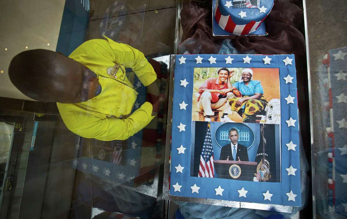 Pastry Chef Svein Ochieng looks at the mock cakes he created featuring photographs of President Barack Obama and his step-grandmother Sarah Obama, and the message "Welcome Home Sir...", in a glass display case outside the Cafe Deli coffee shop, which a manager said Obama visited many years ago before he was a public figure, in Nairobi, Kenya Wednesday, July 22, 2015. In his first trip to Kenya since he was a U.S. senator in 2006, Obama is scheduled to arrive in Kenya on Friday, the first stop on his two-nation African tour in which he will also visit Ethiopia. (AP Photo/Ben Curtis)