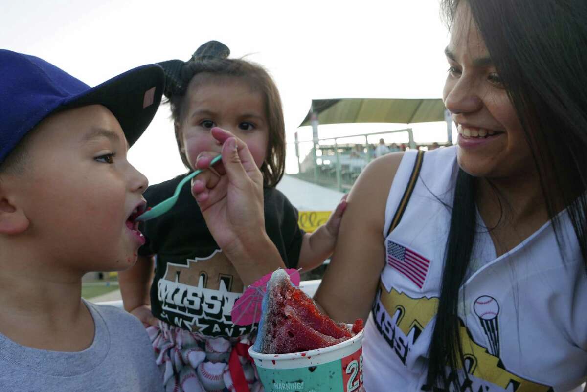 Zaiden, left, and Leilani Rodriguez enjoy shaved ice with the help of their mother, Desiree Gonzales, at Wolff Stadium on Wednesday, July 22, 2015. The San Antonio Missions were hosting the Frisco Roughriders.