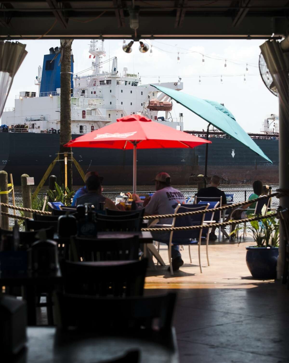 People enjoy a brunch at the Neches River Wheelhouse as a large ship passes by on the river Saturday morning. The Neches River Wheelhouse serves brunch on Saturday and Sunday from 10 a.m. to 2 p.m. and offers brunch seating in their new Paiapa outdoor section. Photo taken Saturday 6/6/15 Jake Daniels/The Enterprise