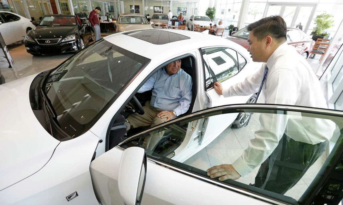 Arnold Arevalo, left, of Richmond, looks at a new car with sales consultant Tony Tran at Sterling McCall Lexus. Despite a slowing economy, sales were strong at Group 1's Houston dealerships as well as its locations around the U.S., the U.K. and Brazil.