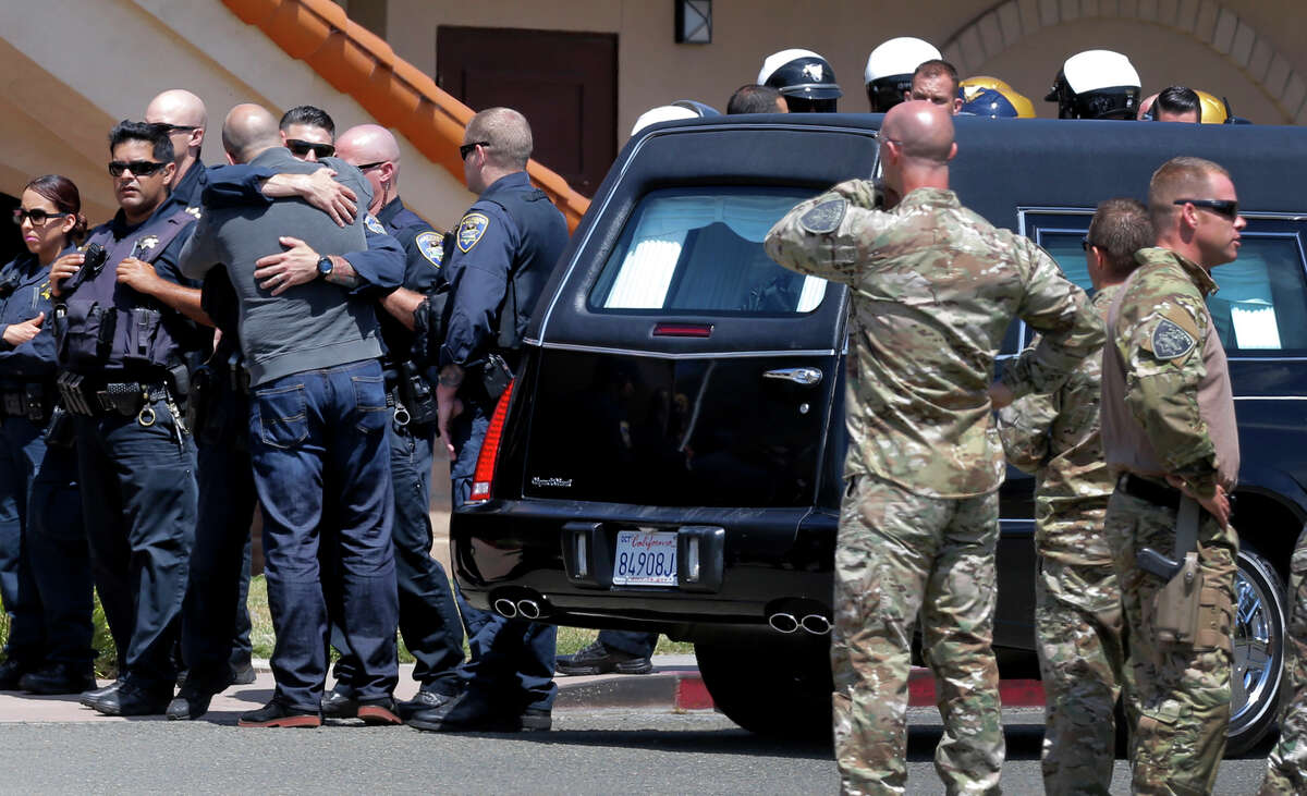 Police personnel surround a hearse carrying the body of Sgt. Scott Lunger to a Hayward funeral home.