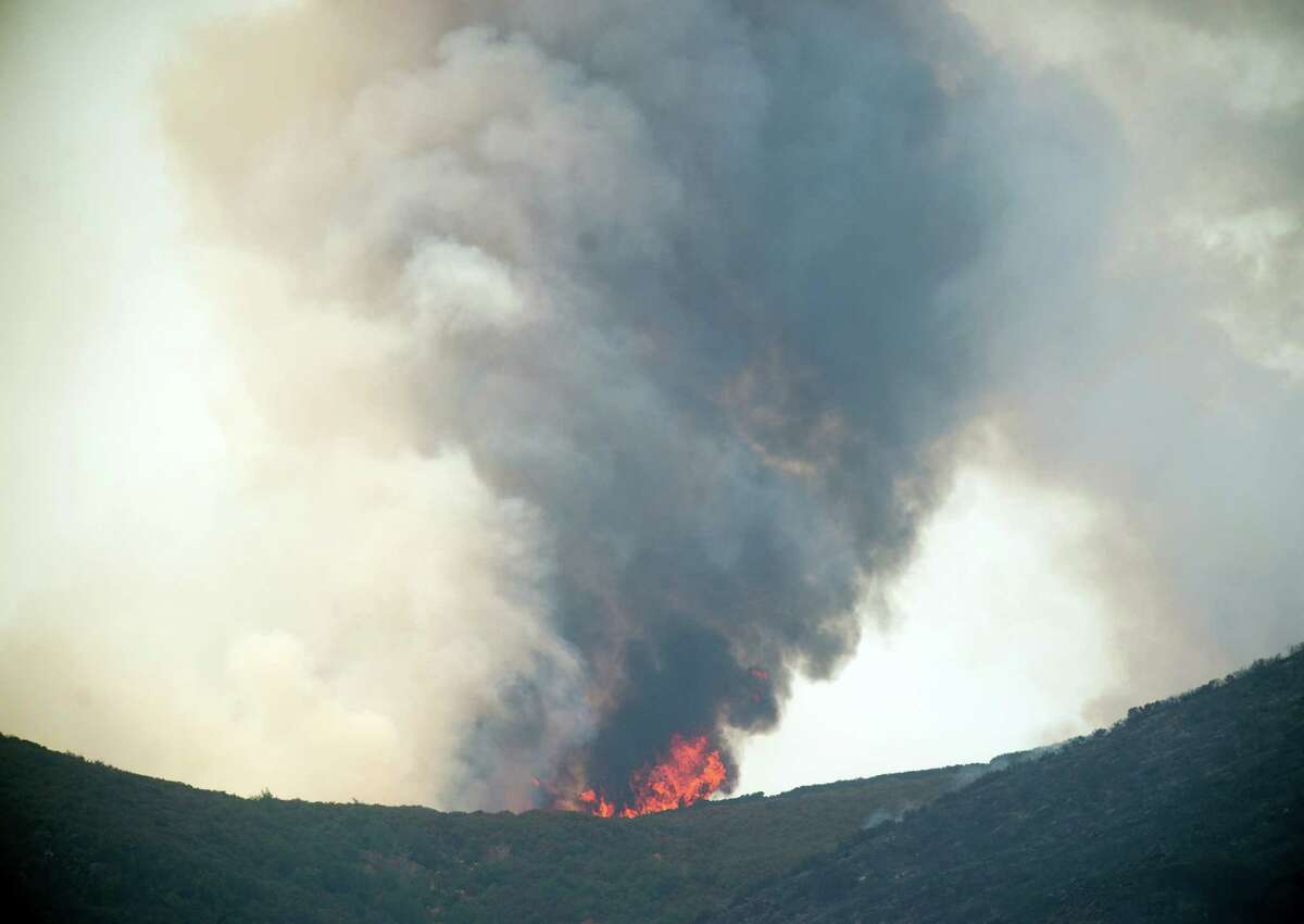 Smoke and flames rise from a ridge top as the Wragg fire burns near Winters, Calif., on Thursday, July 23, 2015. According to Cal Fire, the blaze scorched more than 6,000 acres and is threatening 200 structures. (AP Photo/Noah Berger)
