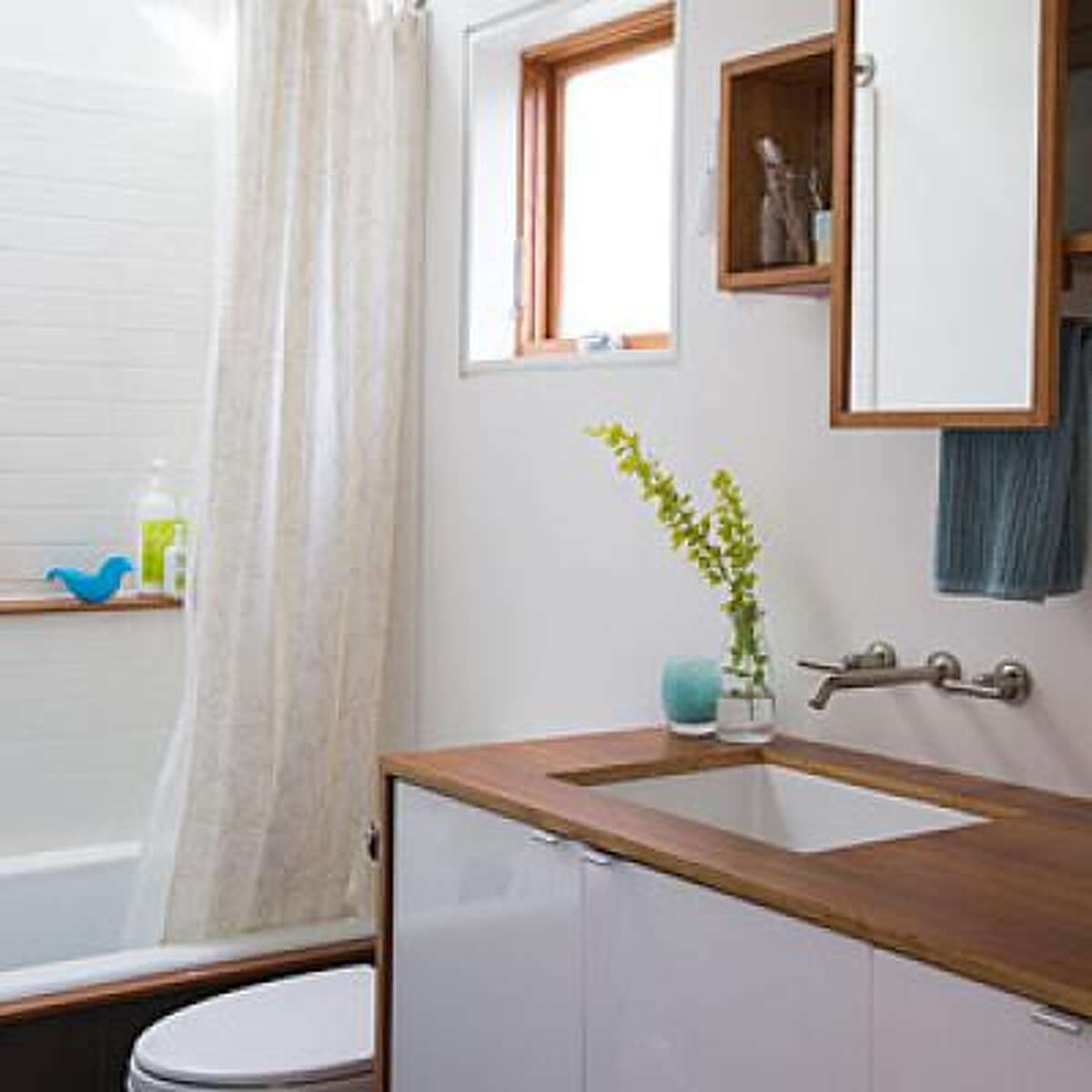 Tweak for efficiency Kyle and Lauren Zerbey are both architects so master-minding the small bathroom their family of four shares was a fun challenge. They chose a small (but deep) tub in exchange for more space outside the tub. The shower itself features a built-in teak shelf for toiletries. They maxed out vanity space by screwing two Ikea vanity units together and topping with teak. Tour the rest of the Zerbey's home