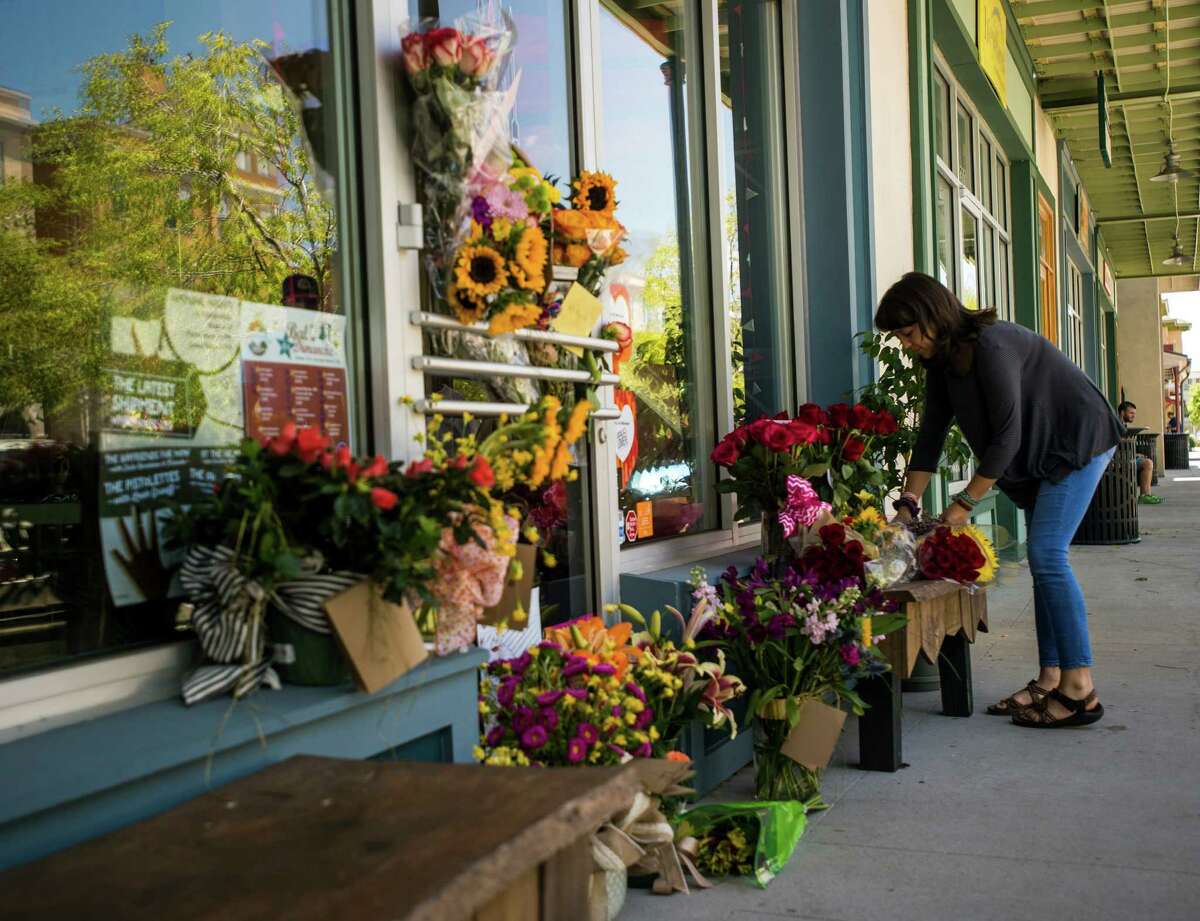 A woman leaves a bouquet of flowers at a makeshift memorial for store co-owner Jillian Johnson at Red Arrow Workshop in River Ranch in Lafayette, La., Friday, July 24, 2015. According to The Daily Advertiser, store co-owner Johnson was among the victims that died following the Thursday night shooting at the Grand 16 theater. (Paul Kieu/The Daily Advertiser via AP)