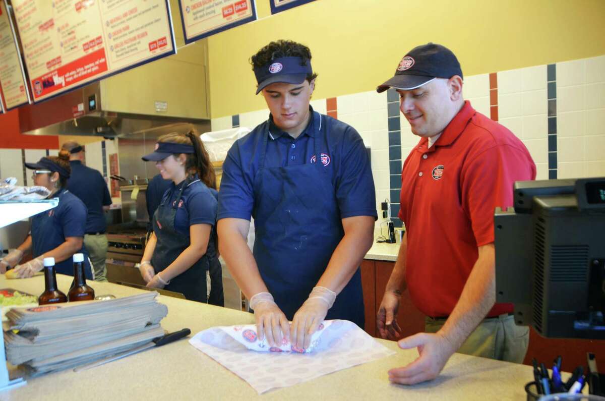 Area General Manager, John Stefanidis, right, oversees as Arthur Delibero, from Ansonia, wraps a sandwich at Jersey Mike‘s Subs on Thursday, July 23, 2015 in Derby, Conn.