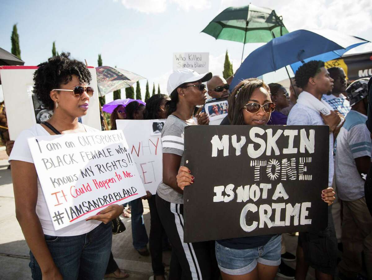 Demonstrators call for the firing and indictment of State Trooper Brian Encinia during a protest on Sunday, July 26, 2015, in Katy. The demonstrators gathered at an apartment complex, lined by Harris County deputies on horseback, to protest against the trooper who arrested Sandra Bland.