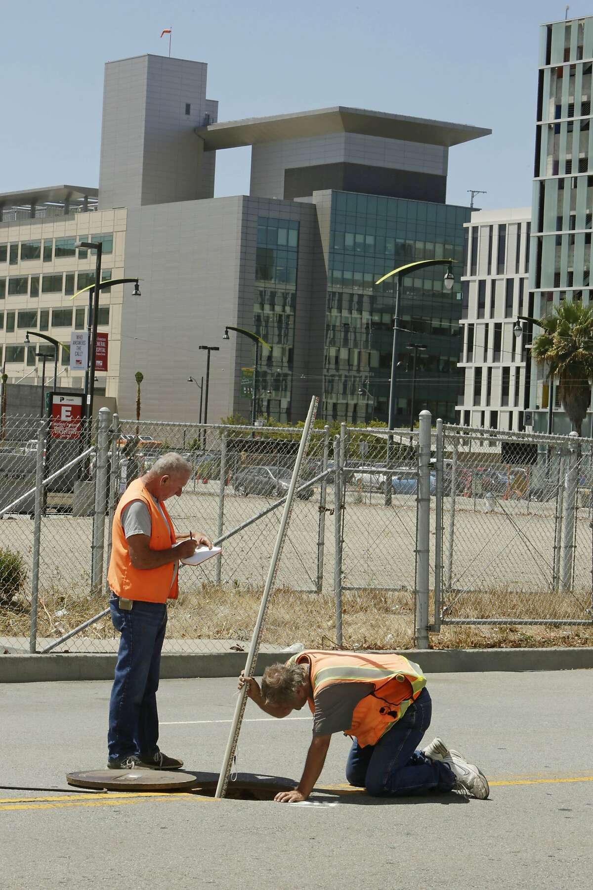 Land surveyors John Seace (l to r) and Frank Montemurro, both of John Seace Land Surveying, work on South Street next to the site of the proposed Golden Gate Warriors arena on Monday, July 27, 2015 in San Francisco, Calif. In the background is seen the UCSF Medical Center at Mission Bay.