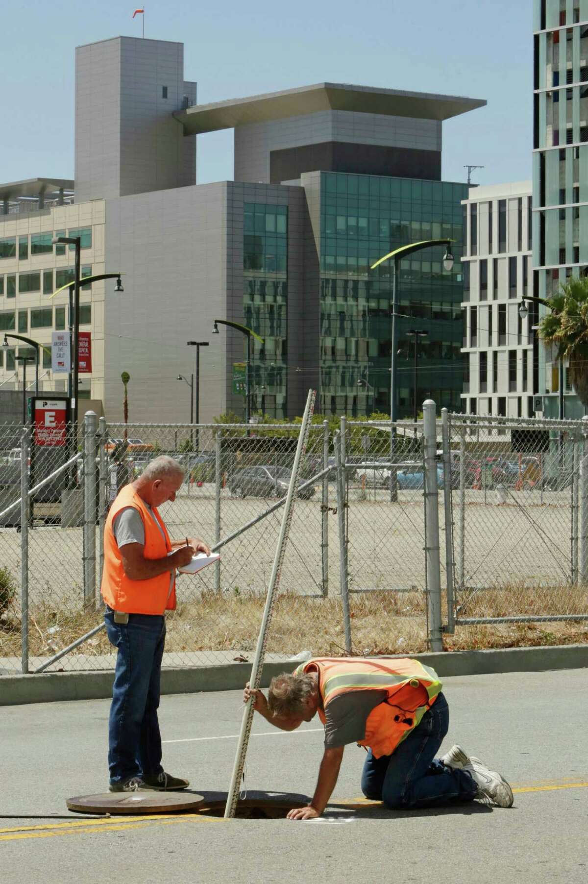 Land surveyors John Seace (left) and Frank Montemurro work on South Street next to the proposed site for a new Golden State Warriors arena. The UCSF Medical Center can be seen in the background.