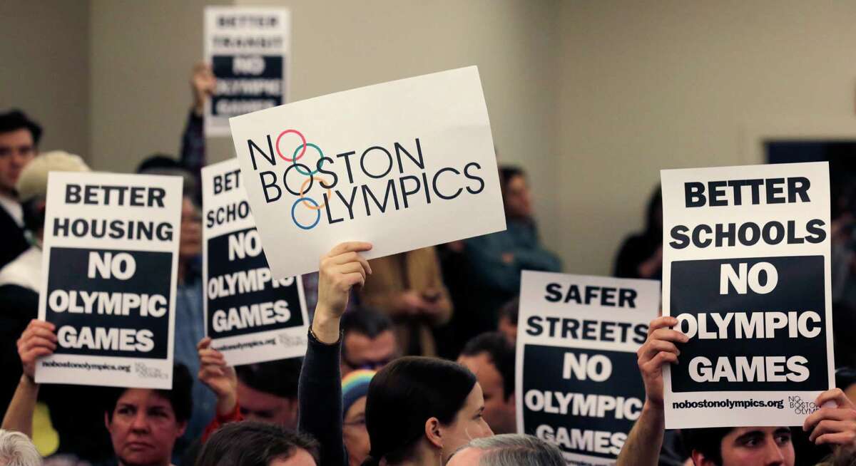 FILE - In this Feb. 5, 2015, file photo, people hold up placards against the Olympic Games coming to Boston, during the first public forum regarding the city's 2024 Olympic bid, in Boston. Boston's mayor delivered a harsh blow to the city's effort to host the 2024 Olympics on Monday, July 27, 2015, when he declared he wouldn't sign any document "that puts one dollar of taxpayer money on the line for one penny of overruns on the Olympics." That document is the host city contract that most in the Olympics consider crucial to any city's success. (AP Photo/Charles Krupa, File) ORG XMIT: NY156