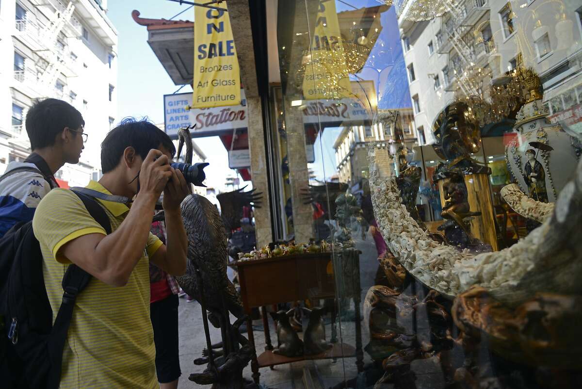 Lang da Yin takes a photo of a mammoth ivory tusk in the window of Rare Art & Antiques store in San Francisco China Town in California, on Tuesday, July 28, 2015. President Obama announced a new measure last Saturday that would eliminate the ivory trade in the United States.