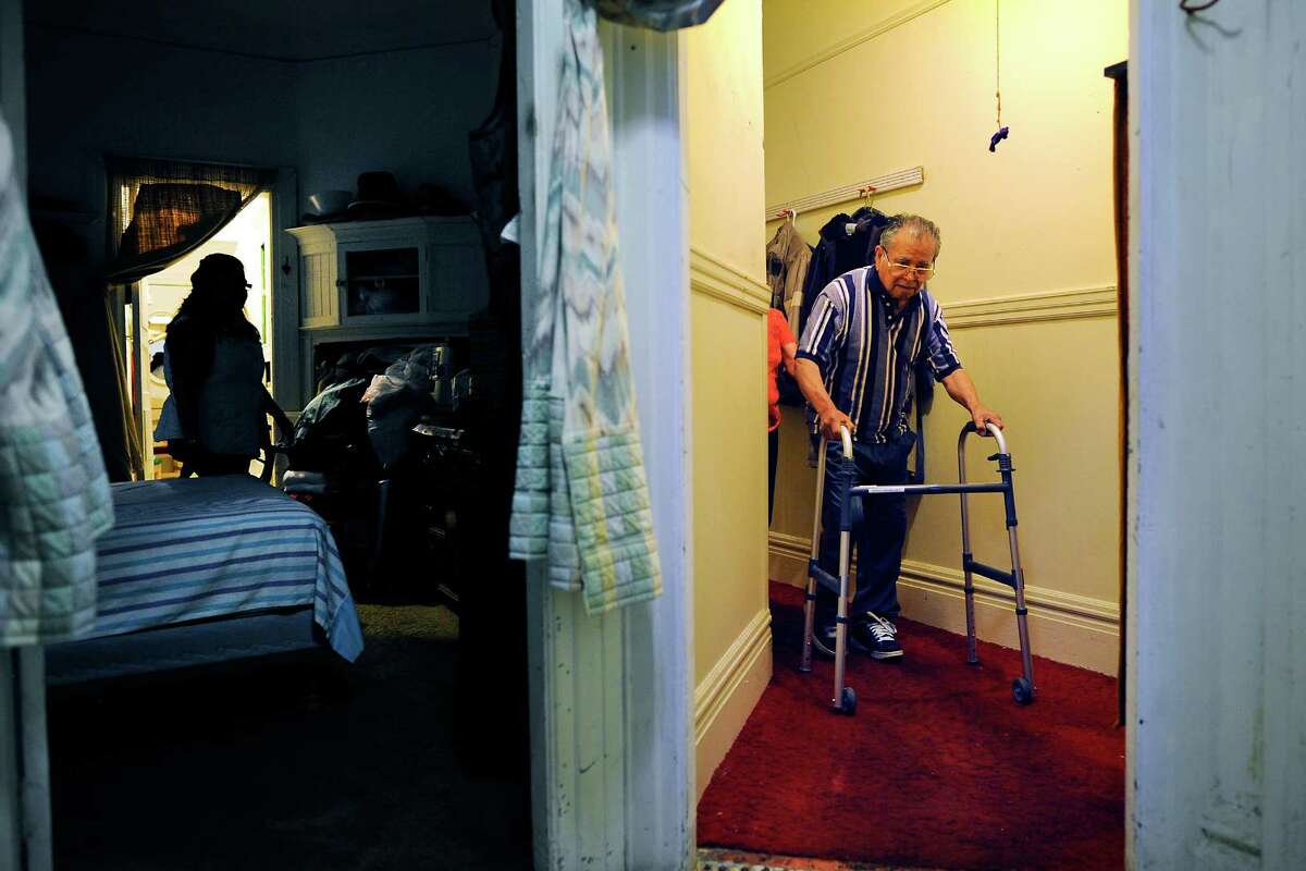 Guillermo Manzanares, 87, is followed by his live-in nurse Marta Reyes as he walks down the hallway of the Mission District apartment he has called home for 50 years but is now being evicted from on July 26, 2015.