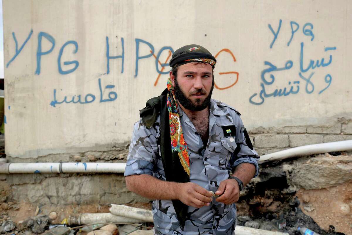 FILE - In this Thursday Jan. 29, 2015 file photo, a Syrian fighter from the Syria-based People's Protection Units better known as the YPG stands in front of a wall covered with graffiti in the town of Sinjar northern Iraq. Turkish jets struck camps belonging to Kurdish militants in northern Iraq Friday and Saturday in what were the first strikes since a peace deal was announced in 2013. The strikes in Iraq targeted the Kurdistan Workers' Party, or PKK, whose affiliates have been effective in battling the Islamic State group. (AP Photo/Bram Janssen, File) ORG XMIT: CAIBS101