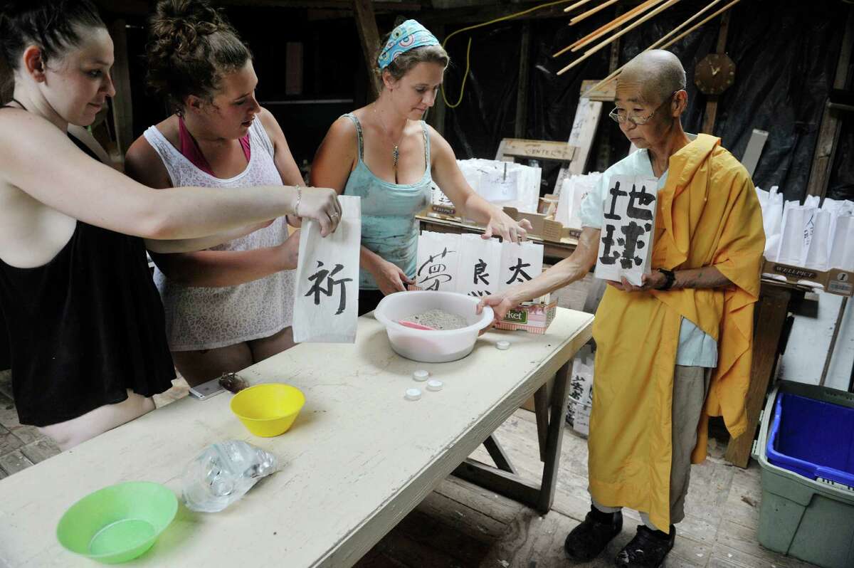 Students, Monique Goodell, left, and Jasmine Rice, second from left, along with their teacher Jeannie O'Neill, third from left, from the Sunrise Opportunity Program in Bennington, VT, work with Jun Yasuda, a Buddhist nun at the Grafton Peace Pagoda on Thursday, July 30, 2015. The women were filling bags with sand and candles as paper lanterns that will be used for the 70th Hiroshima commemoration ceremony being held at the Grafton Peace Pagoda. The Sunrise Opportunity Program is an alternative high school for pregnant and parenting youth. (Paul Buckowski / Times Union)
