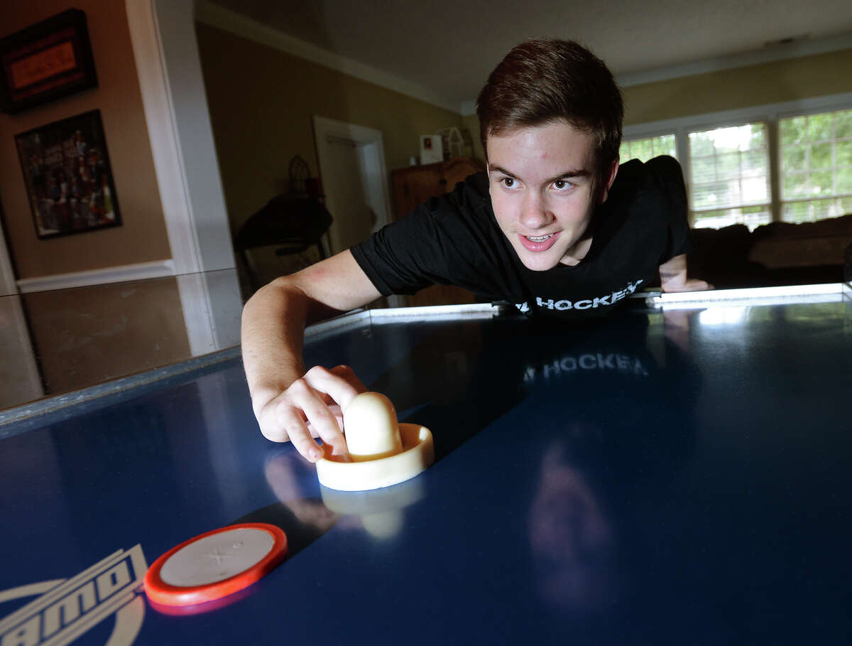 Colin Cummings poses for a photo at his family's air hockey table Thursday afternoon. Cummings, 16, defeated four-time champion Billy Stubbs at the 2015 Rocky Mountain State Games to become the youngest ever air hockey world champion. Cummings has been playing competitively for six years and is a recent transplant to Beaumont from Houston. He will be attending West Brook High School in the fall, where he hopes to start an air hockey club. Photo taken Thursday 7/30/15 Jake Daniels/The Enterprise