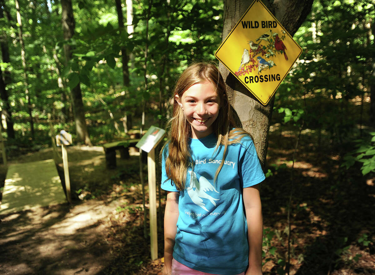 Kaitlyn Lapine, 10, of Monroe, stands in the Blue Jay Bird Sanctuary that she recently constructed with the assistance of friends and family in the woods behind her home in Monroe, Conn. on Thursday, July 23, 2015. The sanctuary includes winding pathways, a wooden bridge, a seating area with a table, and a variety of bird houses and informational displays.