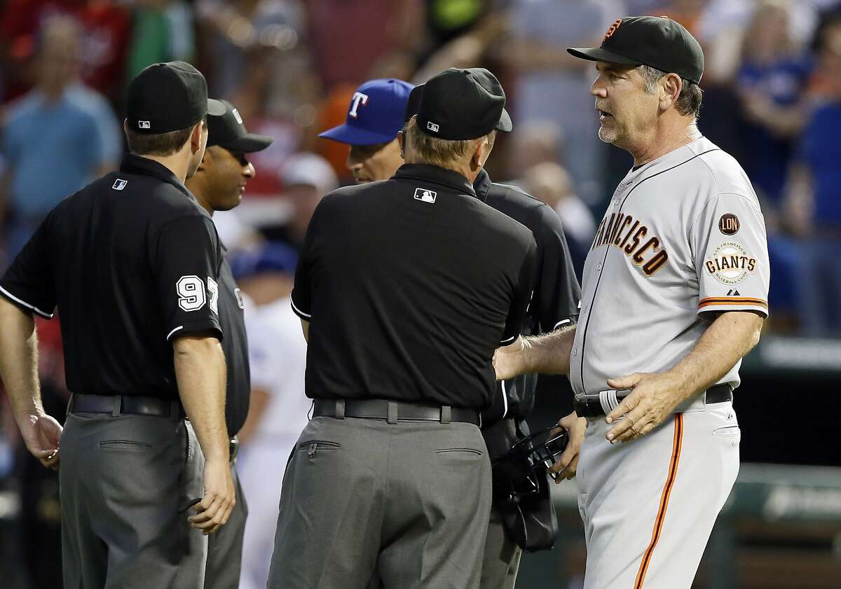 San Francisco Giants manager Bruce Bochy, right, and Texas Rangers manager Jeff Banister, rear, talk to members of the umpiring crew after a benches clearing argument between both teams in the fourth inning of a baseball game Friday, July 31, 2015, in Arlington, Texas.