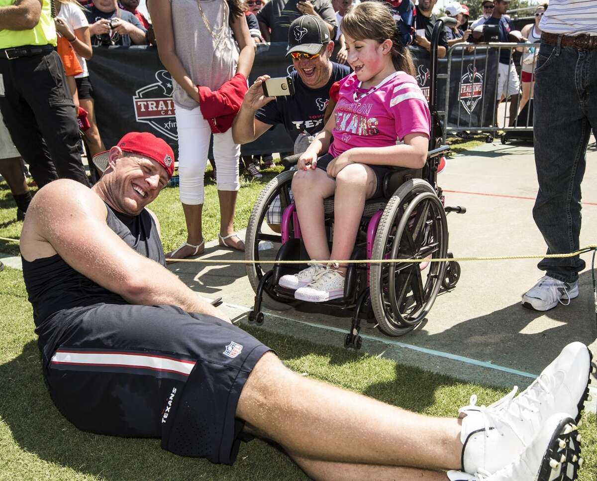 J.J. Watt shares a laugh with fans Pete Cassidy and his daughter, Haley, 11, following practice during Texans training camp on Sunday, Aug. 2.