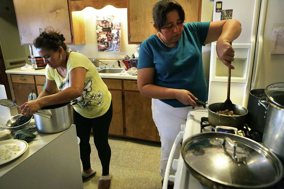 Yanira Lopez Lucas, left, from Guatemala, and Eliud Echeverria from Honduras, prepare a meal of chicken mole and rice and beans for immigrants who just arrived at a San Antonio shelter after being released from South Texas detention centers.