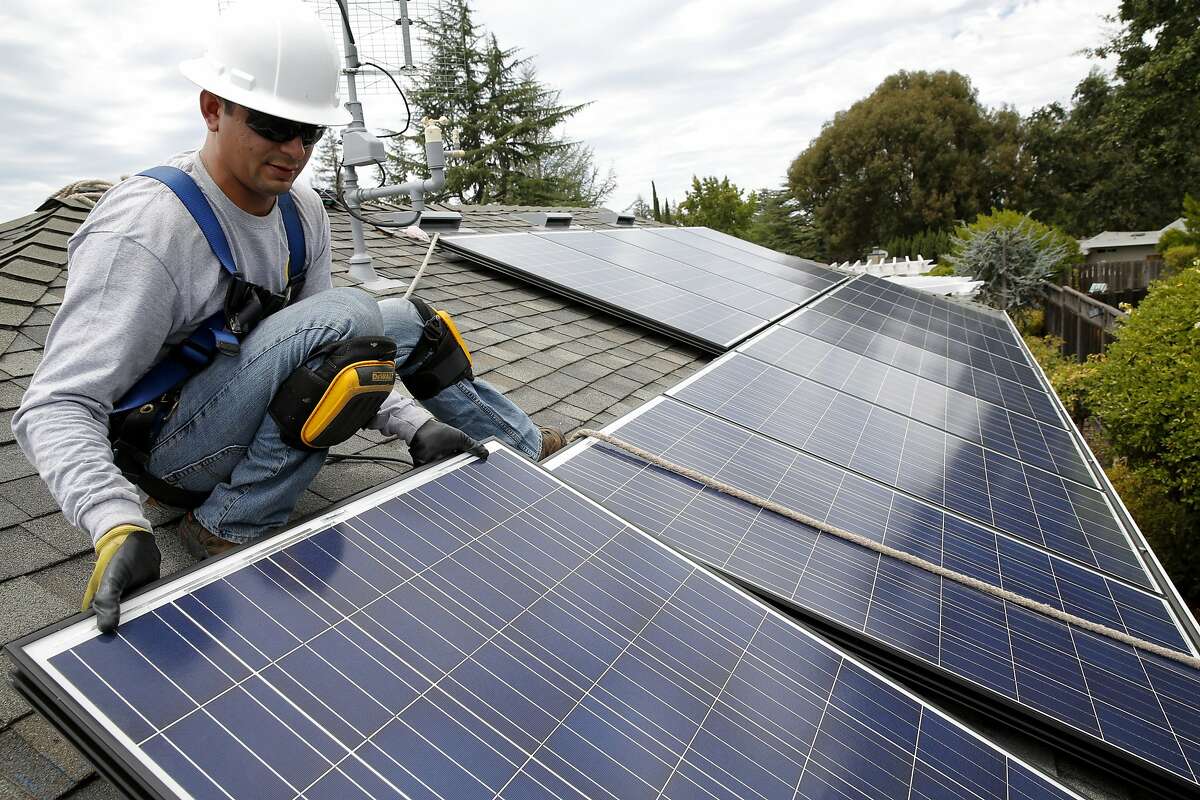 Jonathan Munoz installs a solar panel on the roof of a house in Los Gatos, California, on Tuesday, Aug. 4, 2015.