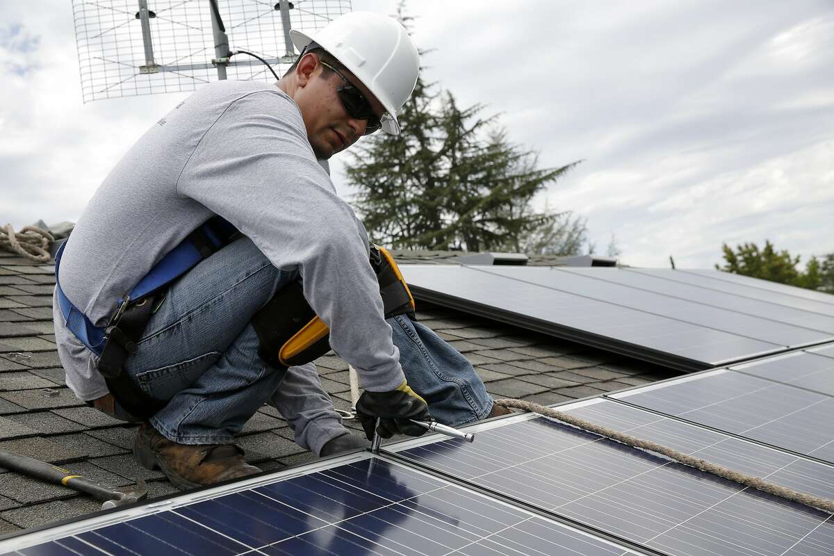 Jonathan Munoz installs a solar panel on the roof of a house in Los Gatos, California, on Tuesday, Aug. 4, 2015.