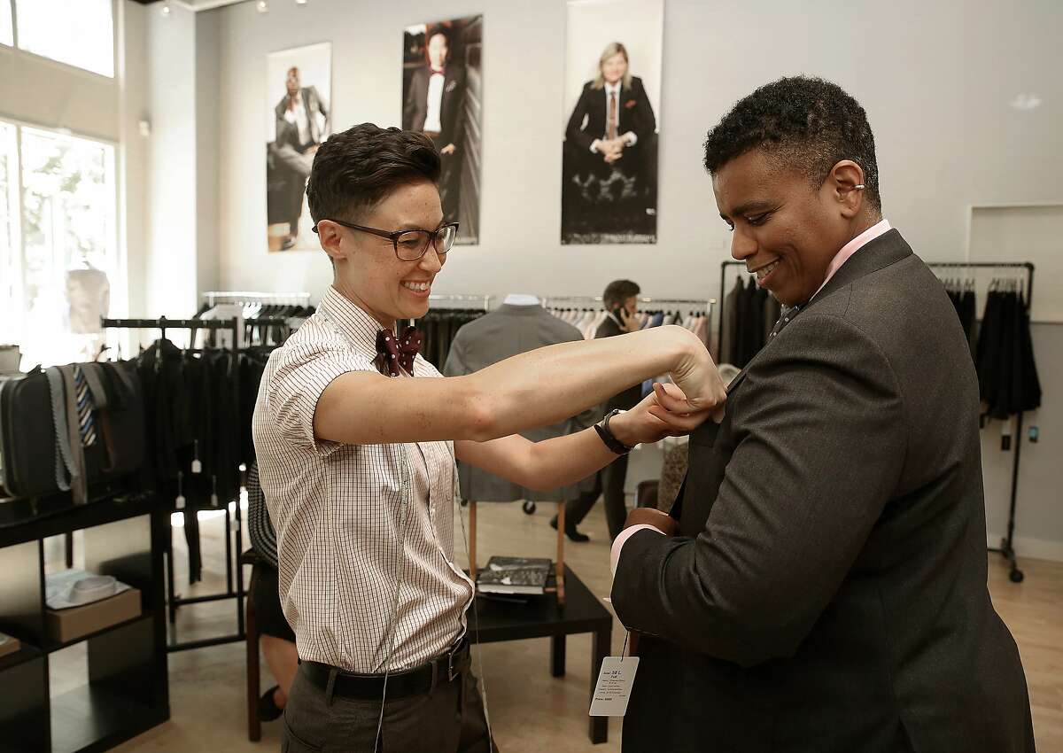 Mr. Dom Brassey (left) of Saint Harridan, a custom suit business for the LGBTQ community in Oakland, Calif., helps Dawn Robinson (right) try on a suit on Monday, August 3, 2015.