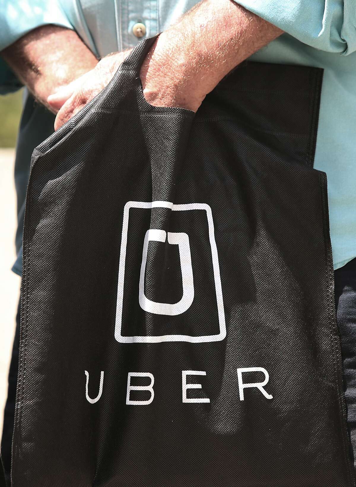 An Uber driver holds an Uber bag during a press conference at the plaza entrance of 450 Golden Gate Ave. in San Francisco, Calif., on Thursday, August 6, 2015. Boutrous and Uber drivers discuss the O'Conner vs. Uber lawsuit seeking to reclassify Uber drivers in California as employees.