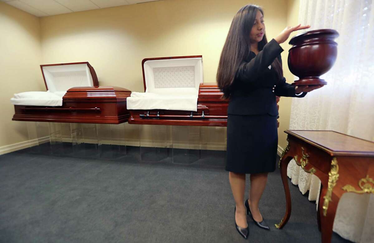 Bery Crispin, of a local funeral home, displays one of the cremation urns that are rising in popularity.﻿