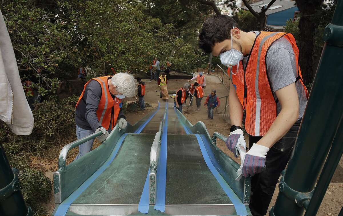 Nearby residents, Michal Kirchberger, (left) and J.T. Trollman sand the giant slide to prepare for painting as dozens of volunteers and neighbors join the San Francisco Public Works August Community Clean Team in the restoration of the Esmeralda Slide Park Plaza in San Francisco, Calif., on Sat. August 8, 2015.