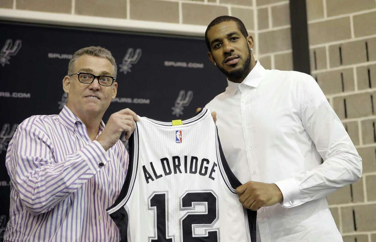 LaMarcus Aldridge, right, poses with San Antonio Spurs general manager R.C. Buford, left, and his new jersey during a news conference at the team’s practice facility as he is formally introduced after he signed with the San Antonio Spurs NBA basketball team, Friday, July 10, 2015, in San Antonio.
