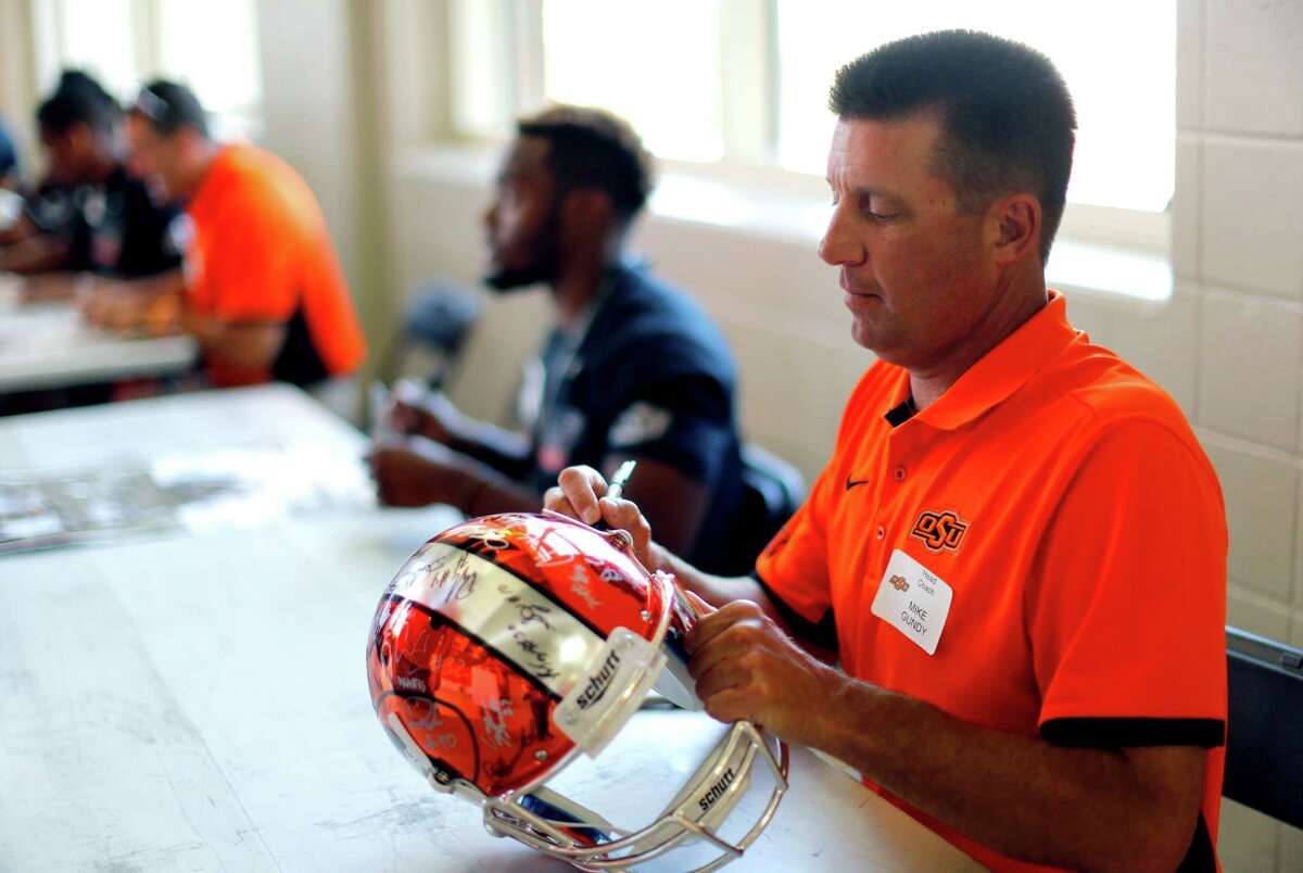 Head coach Mike Gundy signs a helmet for a fan during Oklahoma State's fan appreciation day at Gallagher-Iba Arena in Stillwater, Okla., Saturday, Aug. 8, 2015.(Sarah Phipps/The Oklahoman via AP) LOCAL STATIONS OUT (KFOR, KOCO, KWTV, KOKH, KAUT OUT); LOCAL WEBSITES OUT; LOCAL PRINT OUT (EDMOND SUN OUT, OKLAHOMA GAZETTE OUT) TABLOIDS OUT; MANDATORY CREDIT