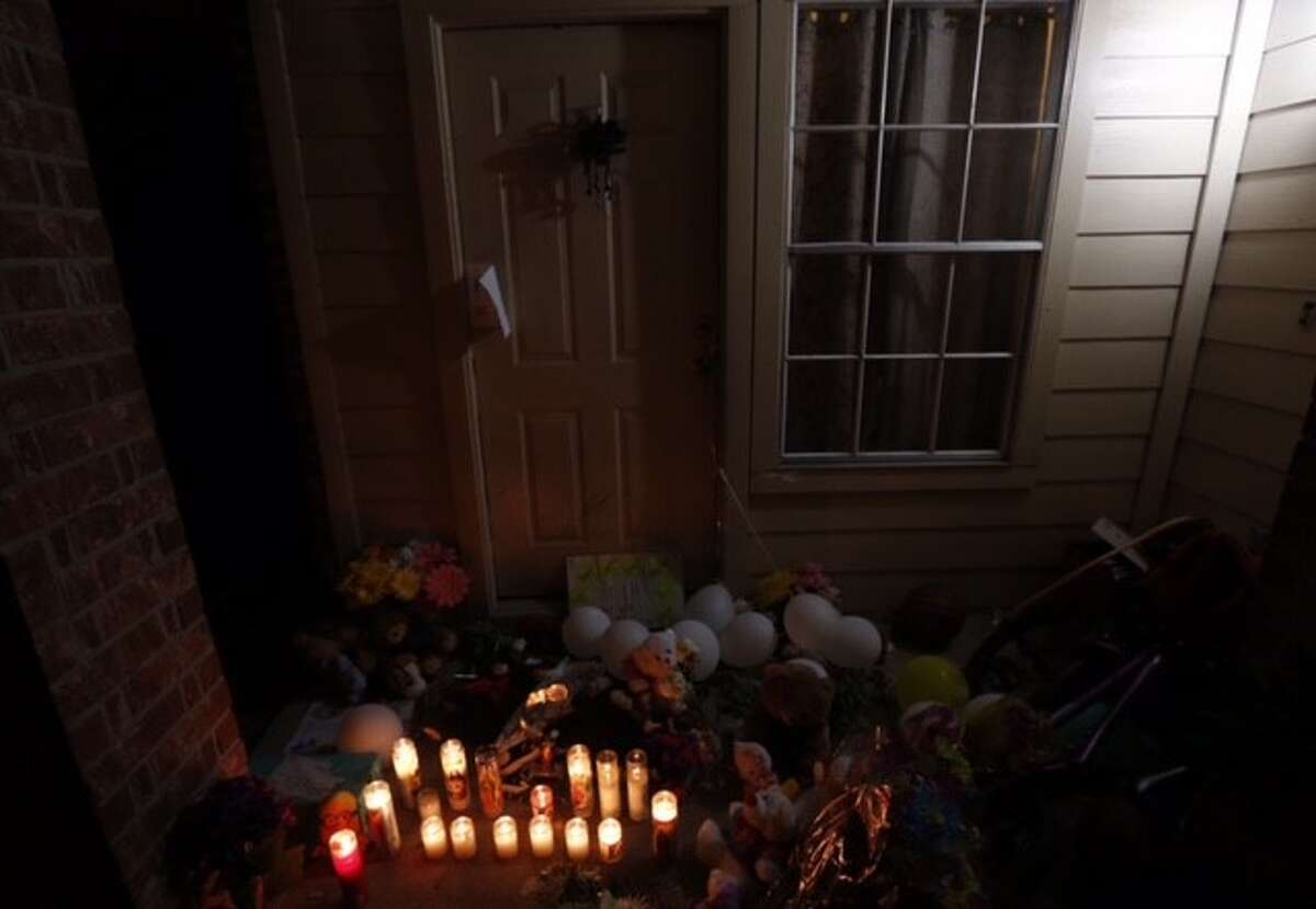 Flowers, balloons, and candles have been placed on the door step of the house where eight people were killed Sunday, Aug. 9, 2015, in Houston.