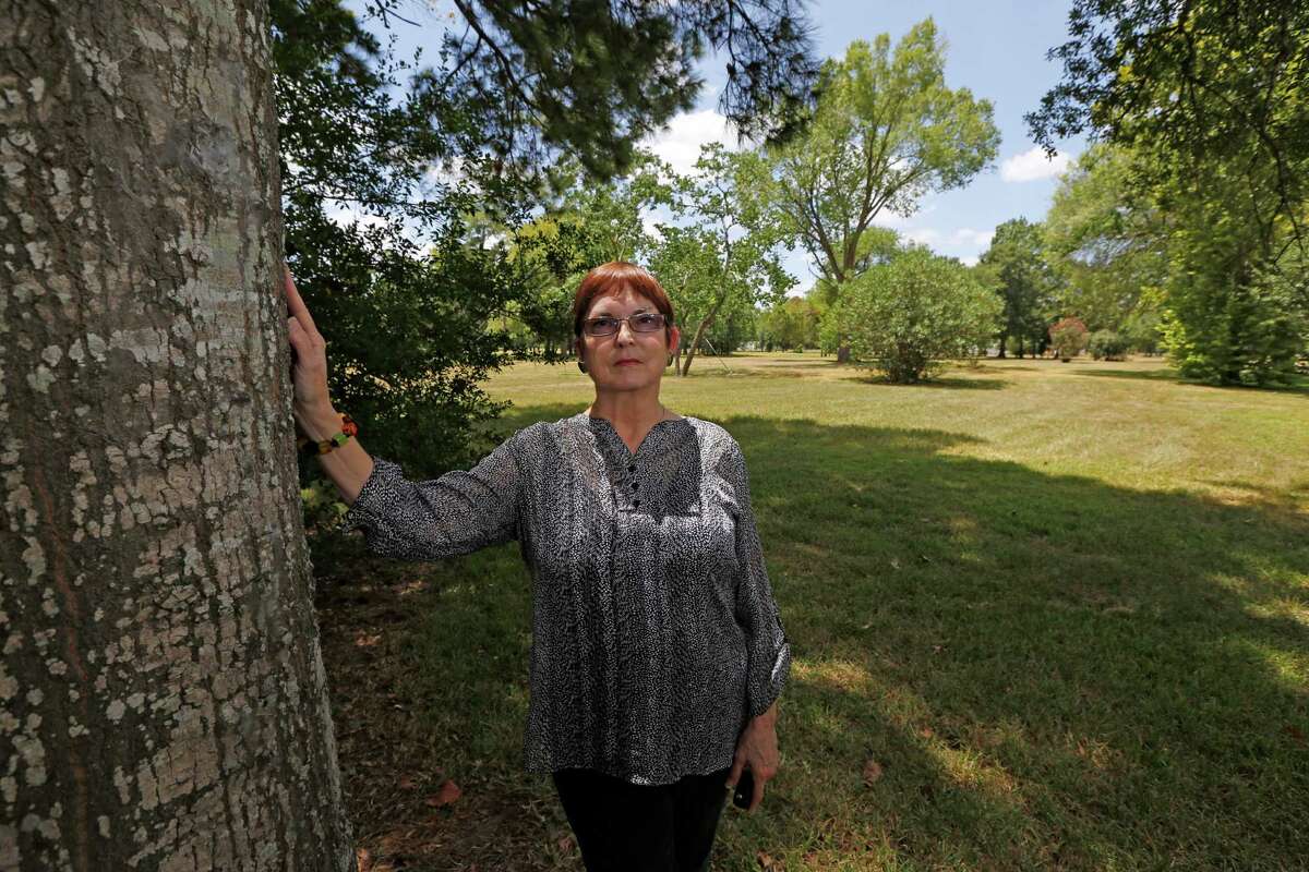 Sheila Wyborny stands next to a 25-foot Wafer Oak tree that she and her husband planted in 1983 when it was about five feet tall Friday, Aug. 7, 2015, in Houston. Sheila and her husband Wendell Wyborny had their home flooded in rain events in 1998, 2001 and 2002. The county's flood control ultimately bought them out and their land is empty. Friday, Aug. 7, 2015, in Houston.