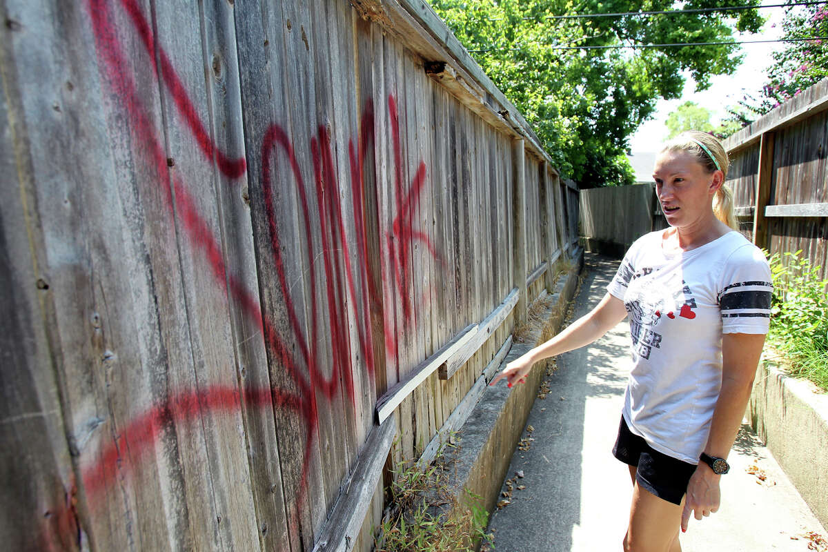 Christine Hetherly-Thigpen, a neighbor trying to keep a watch on tagging activity in the area, inspects a fresh marking with red paint near the intersection of Woodstream and Peppermill Run as a rash of spray paint tagging and defacement occurs near the Grove at Oak Meadow subdivision in northwest San Antonio overnight Wednesday, August 12, 2015.