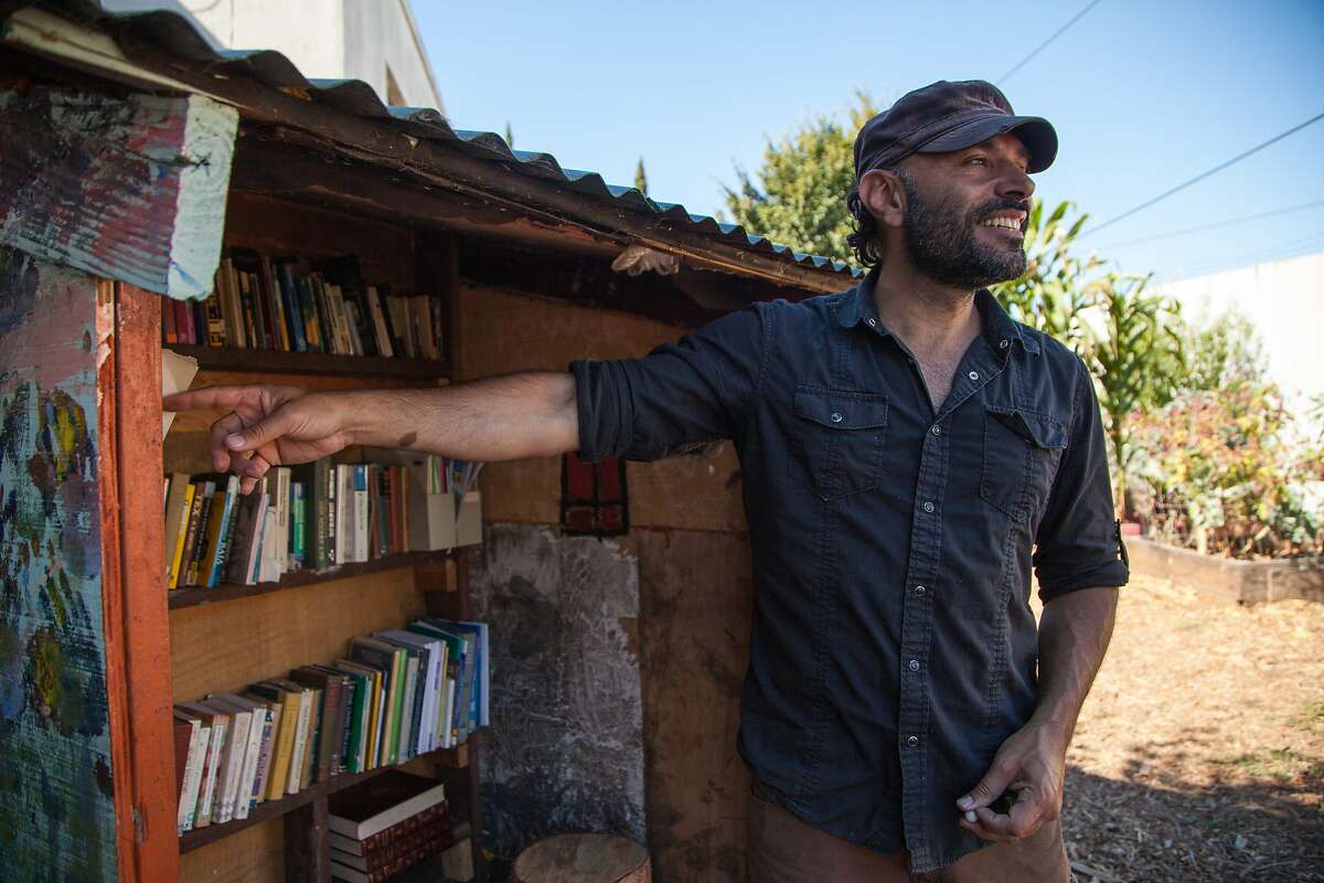 Jaime Omar Yassin checks out the books at the "people's library" and community garden next to the abandoned Miller Avenue Library, Wednesday, Aug. 12, 2015, in Oakland, Calif.