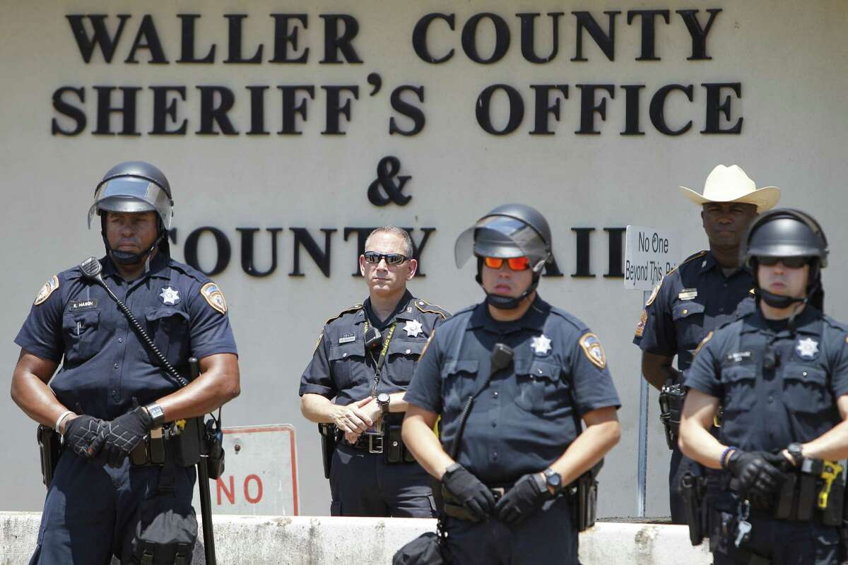 Law officials keep watch on a protest by the New Black Panther Huey P. Newton Gun Club for Sandra Bland and other black victims who have died at the hands of police outside the Waller County Sheriff's Office, Wednesday, Aug. 12, 2015, in Hempstead, Texas. (Steve Gonzales /Houston Chronicle via AP) MANDATORY CREDIT