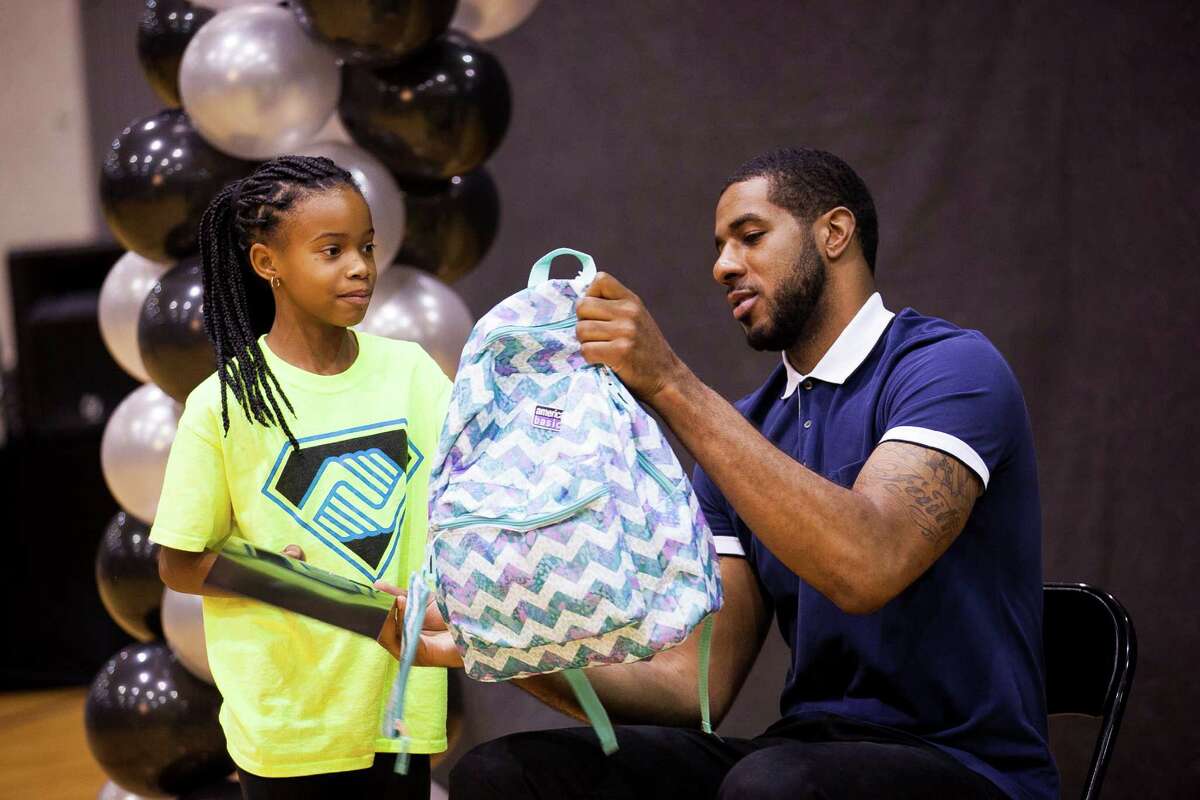 Spurs forward LaMarcus Aldridge hands Anaiya Trussell, 10, a backpack during this year's back-to-school bash, hosted by LaMarcus Aldridge and H-E-B held for 200 students from 3rd Ð 5th grades and their families on Sat. Aug. 15, 2015 at the George Gervin Academy. Students received a backpack filled with a year?•s worth of school supplies.