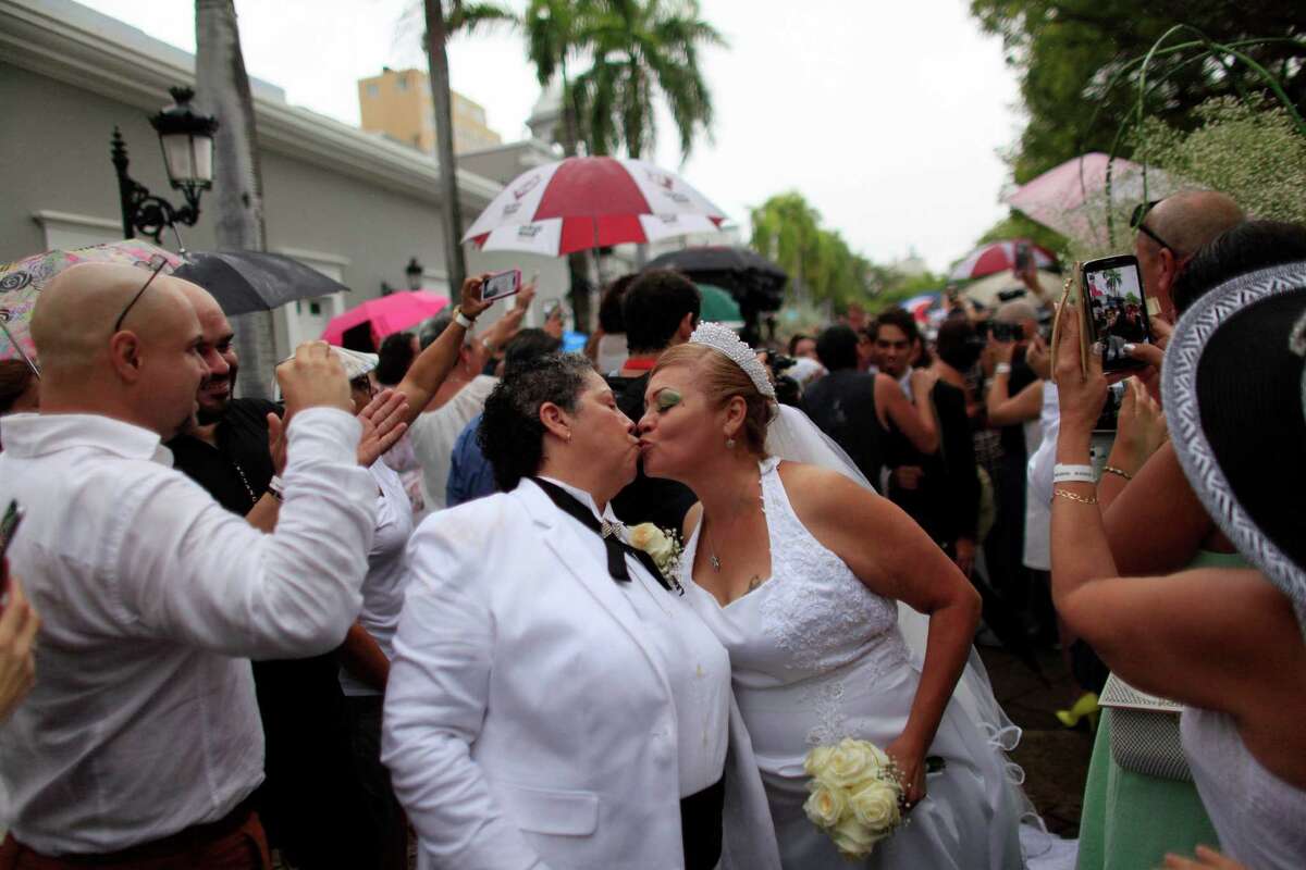 Alma Rosado,left, and Flor Maria Montijo, right, kiss after their wedding during a mass same-sex wedding in San Juan, Puerto Rico, Sunday, Aug. 16, 2015. Over 60 couples from around the region gathered in Puerto Rico?’s capital to exchange vows at a same-sex marriage ceremony. (AP Photo/Ricardo Arduengo)