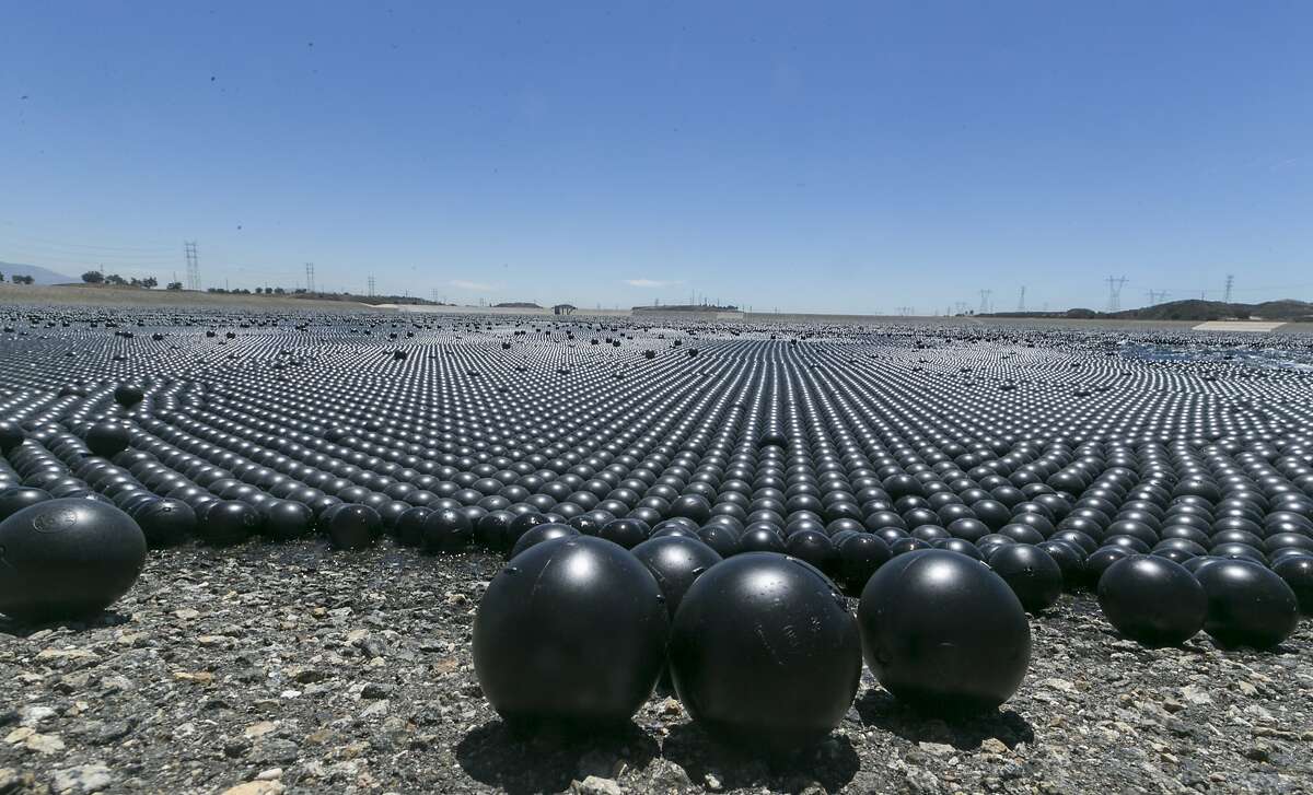Over 90 million plastic balls cover the Los Angeles Reservoir in the Sylmar area of Los Angeles Wednesday, Aug. 12, 2015. The city has completed a program of covering open-air reservoirs with floating "shade balls" to protect water quality. The 4-inch-diameter plastic balls block sunlight from penetrating the 175-acre surface of the reservoir, preventing chemical reactions that can cause algae blooms and other problems. (AP Photo/Damian Dovarganes)