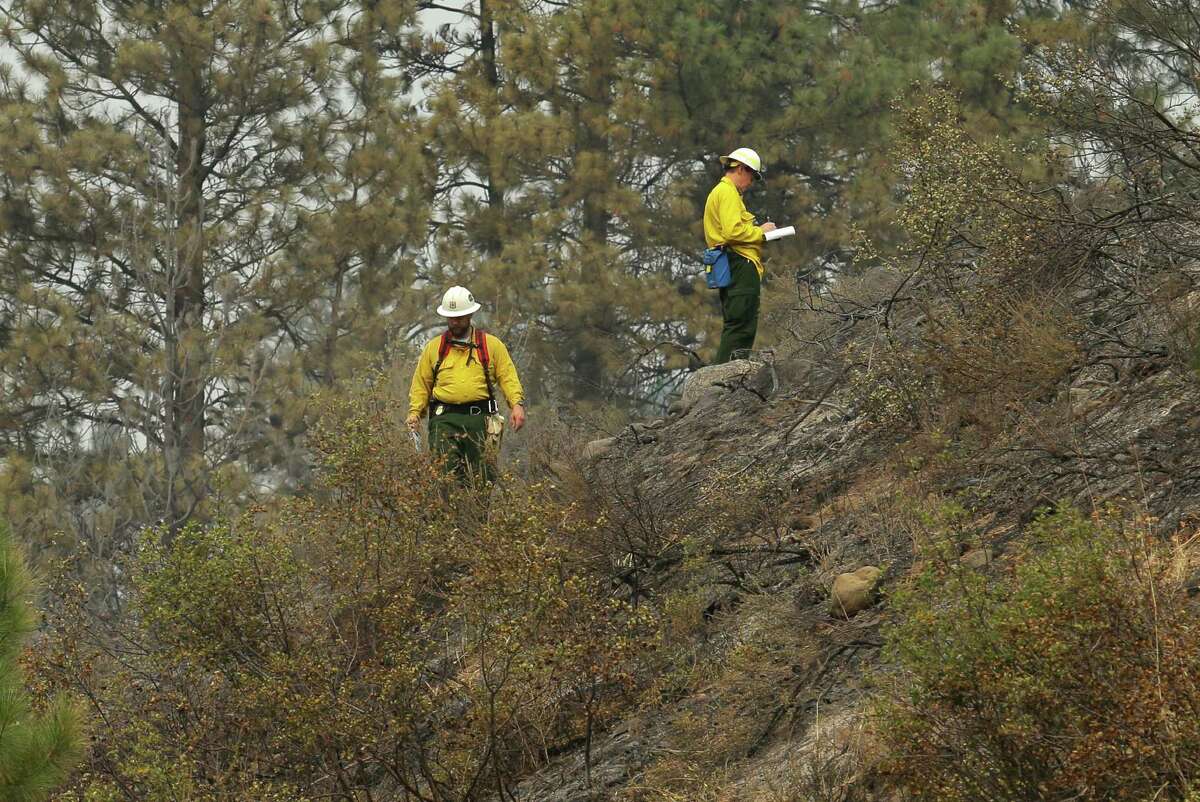 Officials take notes and walk on a hillside near Woods Canyon Road near Twisp, Wash. Thursday, Aug. 20, 2015. Three firefighters were killed Wednesday along the road while fighting a wildfire. (AP Photo/Ted S. Warren)