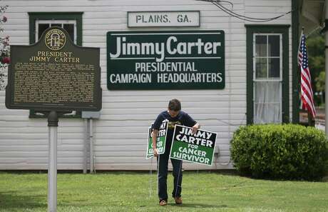 Jill Stuckey places "Jimmy Carter for Cancer Survivor" signs in Plains, Ga., Thursday in advance of the former president's return to his hometown.