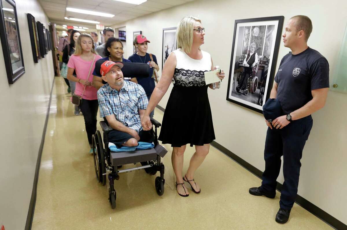 Jackie Dowling, center, speaks to firefighter Mike Miller, right, as she and her husband, Houston Fire Dept. Captain William "Iron Bill" Dowling, left, go to a presentation ceremony of a transport van to the family on Thursday in Houston.